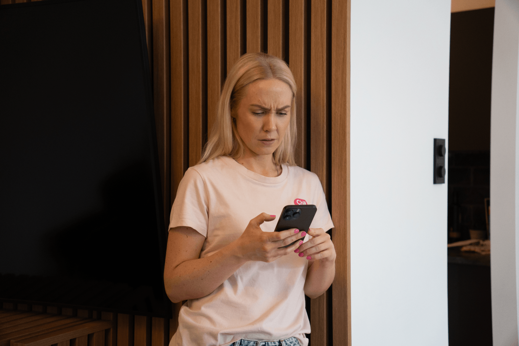 Kvinne ser rart på mobilen si, overrasket sint blikk
