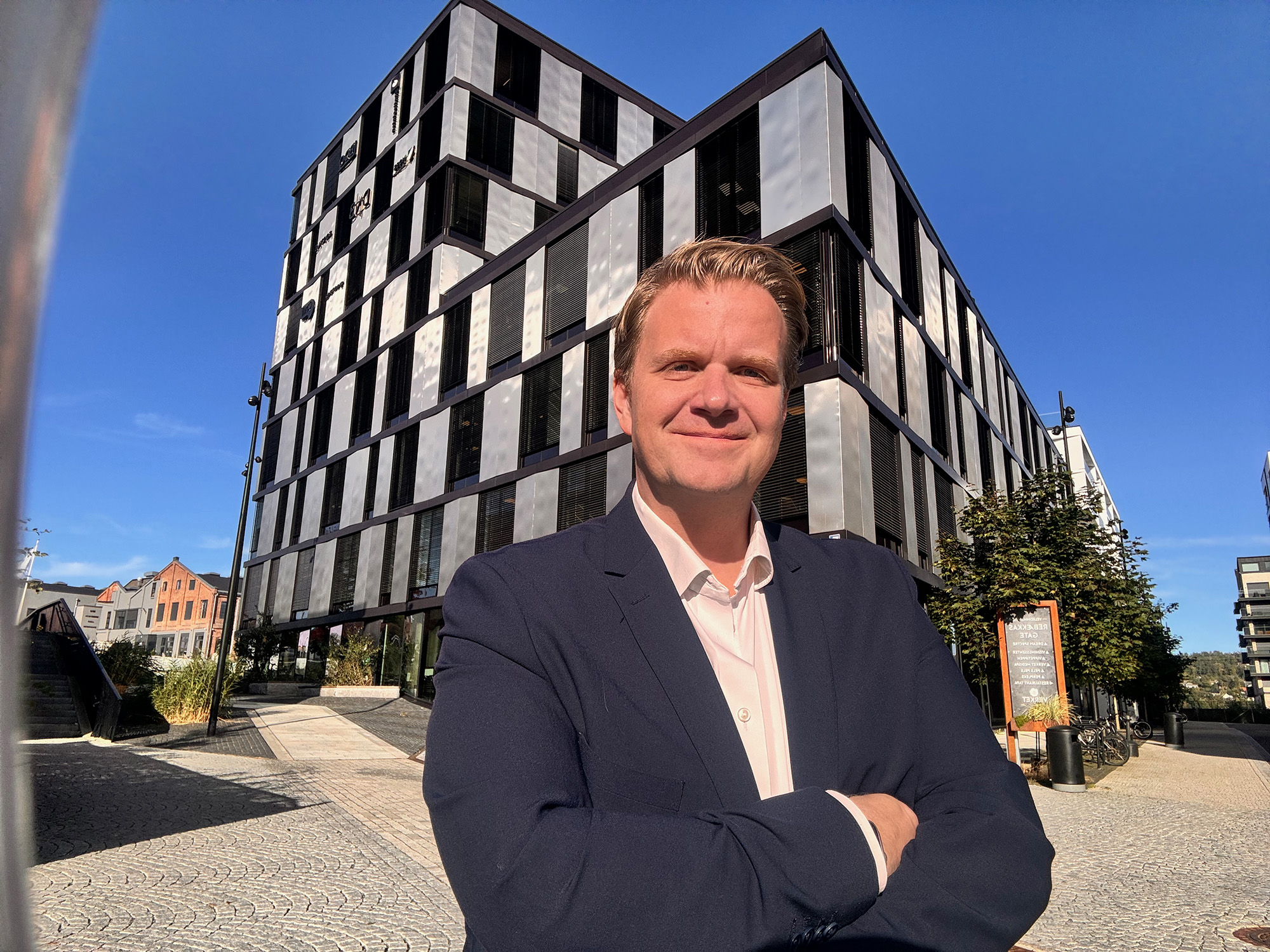 Mann i dress står foran moderne kontorlokaler i Moss